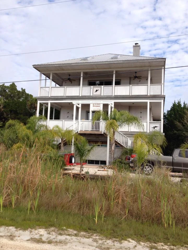 Straight-on view of a coastal-style home in Crystal River, Florida along the Gulf Coast, featuring a freshly painted white exterior with gray accents, showcasing the beautifully painted double balconies and railings, completed by T&B Paint Pros.