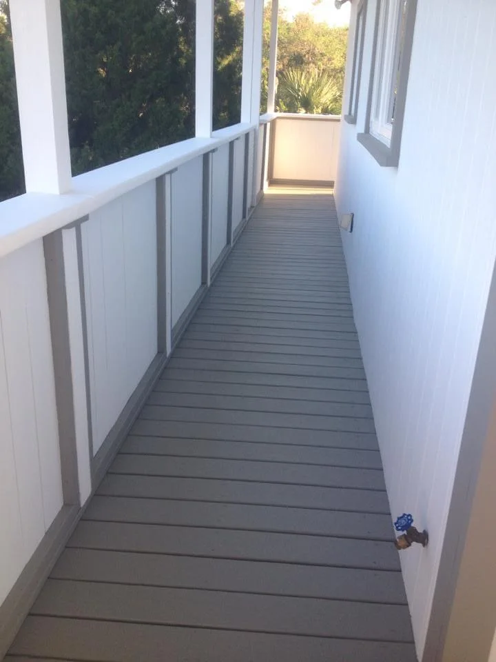Close-up view of a coastal-style home balcony in Crystal River, Florida, with a freshly painted gray deck and white railings with gray accents, professionally painted by T&B Paint Pros.