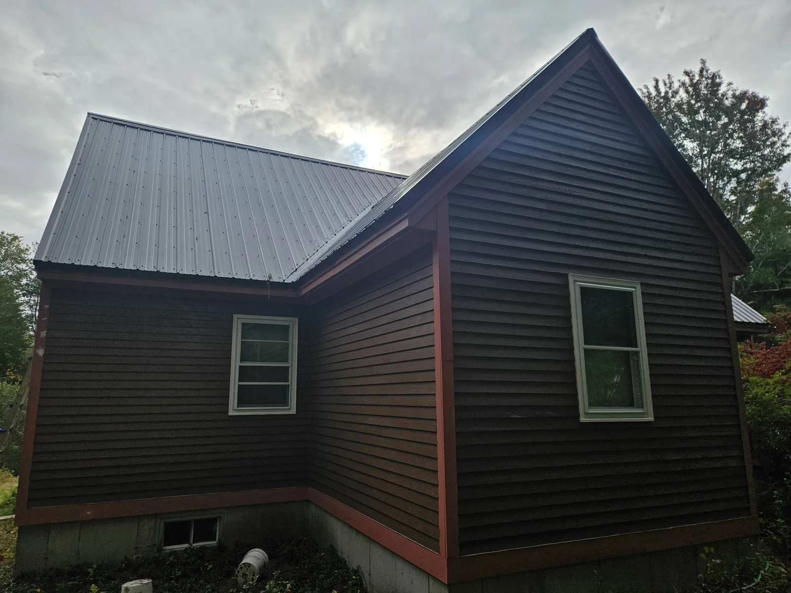 Freshly painted dark brown house with red trim in Harvey, NH, completed by T&B Paint Pros. tbpaintpros Flagler County Florida experienced painter specializing in exterior home painting for long-lasting durability and curb appeal.